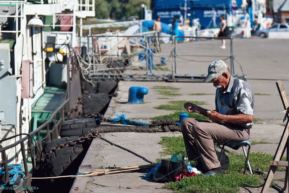 Fisherman in a silver shirt on the pier of Azov