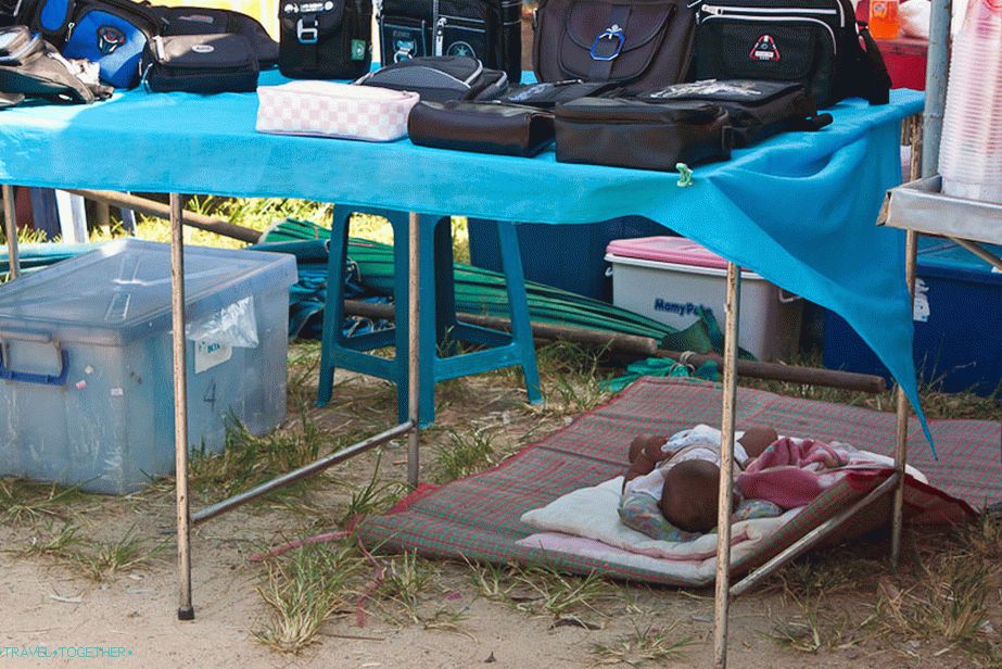 The baby sleeps in the market under the table