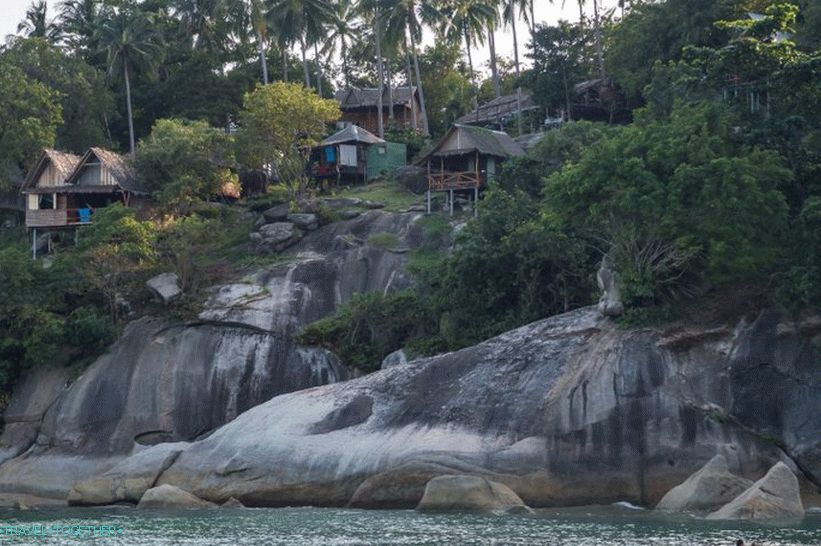 Right behind the river there are rocks with houses.