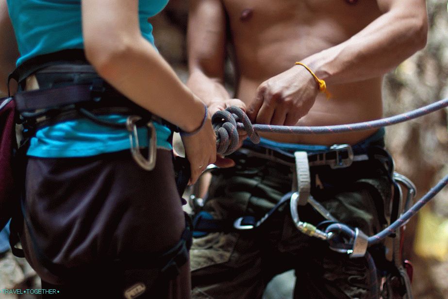 The instructor shows how to attach the carabiner to the harness